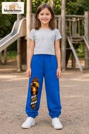 Mädchen trägt blaue Jogginghose mit Good Days Palmen-Print, von vorn auf dem Spielplatz.