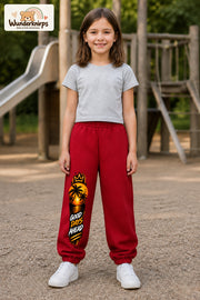 Mädchen trägt rote Jogginghose mit Good Days Palmen-Print, von vorn auf dem Spielplatz.