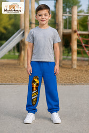 Junge trägt blaue Jogginghose mit Higher Life Palmen-Print, von vorn auf dem Spielplatz.