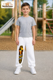 Junge trägt weiße Jogginghose mit Higher Life Palmen-Print, von vorn auf dem Spielplatz.