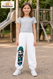 Mädchen trägt weiße Jogginghose mit Sei du selbst Panda-Print, von vorn auf dem Spielplatz.
