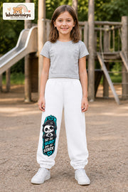 Mädchen trägt weiße Jogginghose mit Sei du selbst Herz-Panda-Print, von vorn auf dem Spielplatz.