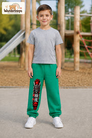 Junge trägt grüne Jogginghose mit Samurai Kirschblüten-Print, von vorn auf dem Spielplatz.
