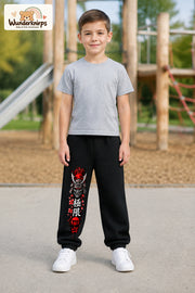 Junge trägt schwarze Jogginghose mit Samurai Kirschblüten-Print, von vorn auf dem Spielplatz.