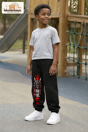 Junge trägt schwarze Jogginghose mit Samurai Kirschblüten-Print, leicht seitlich auf dem Spielplatz.