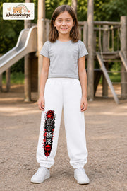 Mädchen trägt weiße Jogginghose mit Samurai Kirschblüten-Print, von vorn auf dem Spielplatz.
