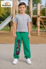 Junge trägt grüne Jogginghose mit Strength Blütenschlange-Print, von vorn auf dem Spielplatz.