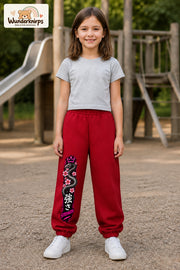 Mädchen trägt rote Jogginghose mit Strength Blütenschlange-Print, von vorn auf dem Spielplatz.