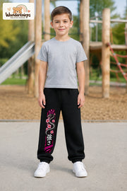 Junge trägt schwarze Jogginghose mit Strength Blütenschlange-Print, von vorn auf dem Spielplatz.