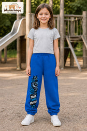Mädchen trägt blaue Jogginghose mit Trust Your Process Schlange-Print, von vorn auf dem Spielplatz.