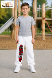 Junge trägt weiße Jogginghose mit Beauty with Bite-Print, von vorn auf dem Spielplatz.