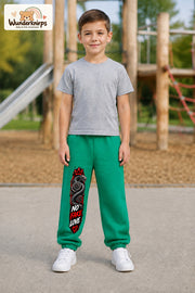 Junge trägt grüne Jogginghose mit No Fake Love Schlange-Print, von vorn auf dem Spielplatz.