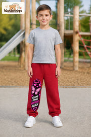 Junge trägt rote Jogginghose mit Kleine Dinge Schmetterling-Print, von vorn auf dem Spielplatz.