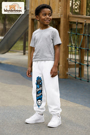 Junge trägt weiße Jogginghose mit Skate Eat Sleep Repeat-Print, leicht seitlich auf dem Spielplatz.