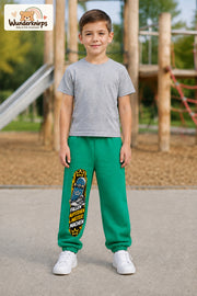 Junge trägt grüne Jogginghose mit Weitermachen Skateschuh-Print, von vorn auf dem Spielplatz.