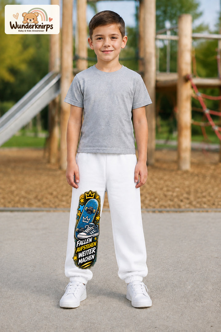 Junge trägt weiße Jogginghose mit Weitermachen Sternen-Board-Print, von vorn auf dem Spielplatz.