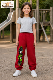 Mädchen trägt rote Jogginghose mit Skate All Day Skull-Print, von vorn auf dem Spielplatz.