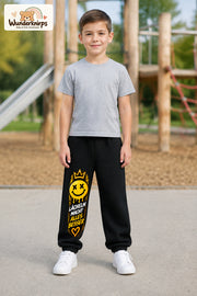 Junge trägt schwarze Jogginghose mit Lächeln macht besser-Print, von vorn auf dem Spielplatz.