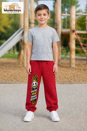Junge trägt rote Jogginghose mit Positive Mind Smiley-Print, von vorn auf dem Spielplatz.