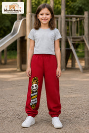 Mädchen trägt rote Jogginghose mit Positive Mind Smiley-Print, von vorn auf dem Spielplatz.
