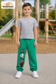 Junge trägt grüne Jogginghose mit Never Stop Smiley-Print, von vorn auf dem Spielplatz.