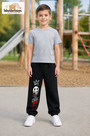 Junge trägt schwarze Jogginghose mit Never Stop Smiley-Print, von vorn auf dem Spielplatz.