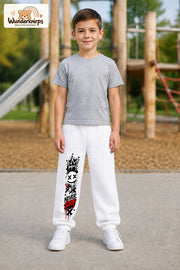 Junge trägt weiße Jogginghose mit Never Stop Smiley-Print, von vorn auf dem Spielplatz.