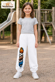 Mädchen trägt weiße Jogginghose mit Play Hard Sportmix-Print, von vorn auf dem Spielplatz.