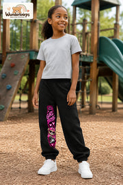 Mädchen trägt schwarze Jogginghose mit Girl Boss Bär-Print, leicht seitlich auf dem Spielplatz.