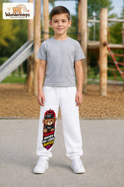 Junge trägt weiße Jogginghose mit Freunde machen bunt Teddy-Print, von vorn auf dem Spielplatz.