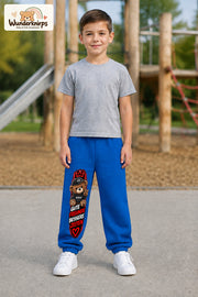 Junge trägt blaue Jogginghose mit Gute Freunde Teddy-Print, von vorn auf dem Spielplatz.