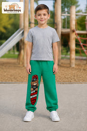 Junge trägt grüne Jogginghose mit Gute Freunde Teddy-Print, von vorn auf dem Spielplatz.