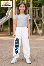 Mädchen trägt weiße Jogginghose mit Born to Be Real Tiger-Print, von vorn auf dem Spielplatz.