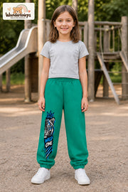 Mädchen trägt grüne Jogginghose mit Wild One Tiger-Print, von vorn auf dem Spielplatz.
