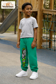 Junge trägt grüne Jogginghose mit Be Brave Tiger-Print, leicht seitlich auf dem Spielplatz.