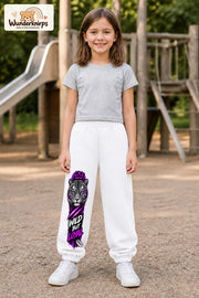 Mädchen trägt weiße Jogginghose mit Wild but Loyal Tiger-Print, von vorn auf dem Spielplatz.