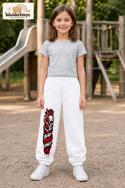 Mädchen trägt weiße Jogginghose mit Bad Vibes Skull-Print, von vorn auf dem Spielplatz.