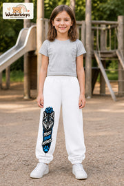 Mädchen trägt weiße Jogginghose mit Trust Your Instincts Wolf-Print, von vorn auf dem Spielplatz.
