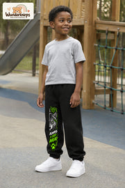 Junge trägt schwarze Jogginghose mit Always Ahead Wolf-Print, leicht seitlich auf dem Spielplatz.