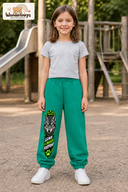 Mädchen trägt grüne Jogginghose mit Bigger Footprint Wolf-Print, von vorn auf dem Spielplatz.