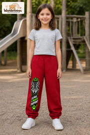 Mädchen trägt rote Jogginghose mit Bigger Footprint Wolf-Print, von vorn auf dem Spielplatz.