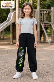 Mädchen trägt schwarze Jogginghose mit Bigger Footprint Wolf-Print, von vorn auf dem Spielplatz.