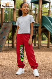 Mädchen trägt rote Jogginghose mit Glück ist Entscheidung-Print, leicht seitlich auf dem Spielplatz.