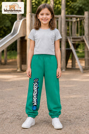 Mädchen trägt grüne Jogginghose mit Wunderknirps Graffiti-Print, von vorn auf dem Spielplatz.
