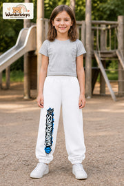 Mädchen trägt weiße Jogginghose mit Wunderknirps Graffiti-Print, von vorn auf dem Spielplatz.