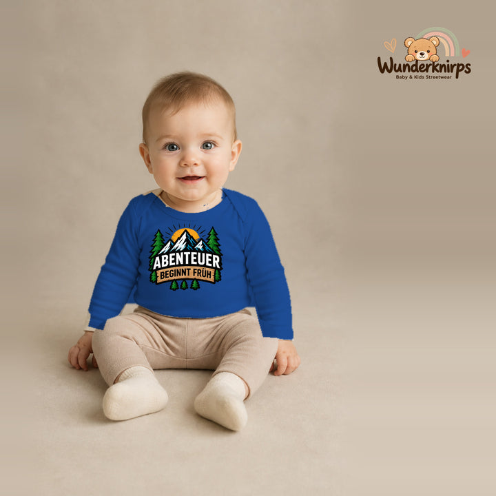 Babybody für Jungen in Blau mit Motiv „Abenteuer beginnt früh“, getragen von einem Kind – Wunderknirps.