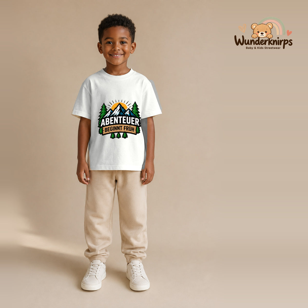 T-Shirt für Jungen in Weiß mit Motiv „Abenteuer beginnt früh“, getragen von einem Kind – Wunderknirps.