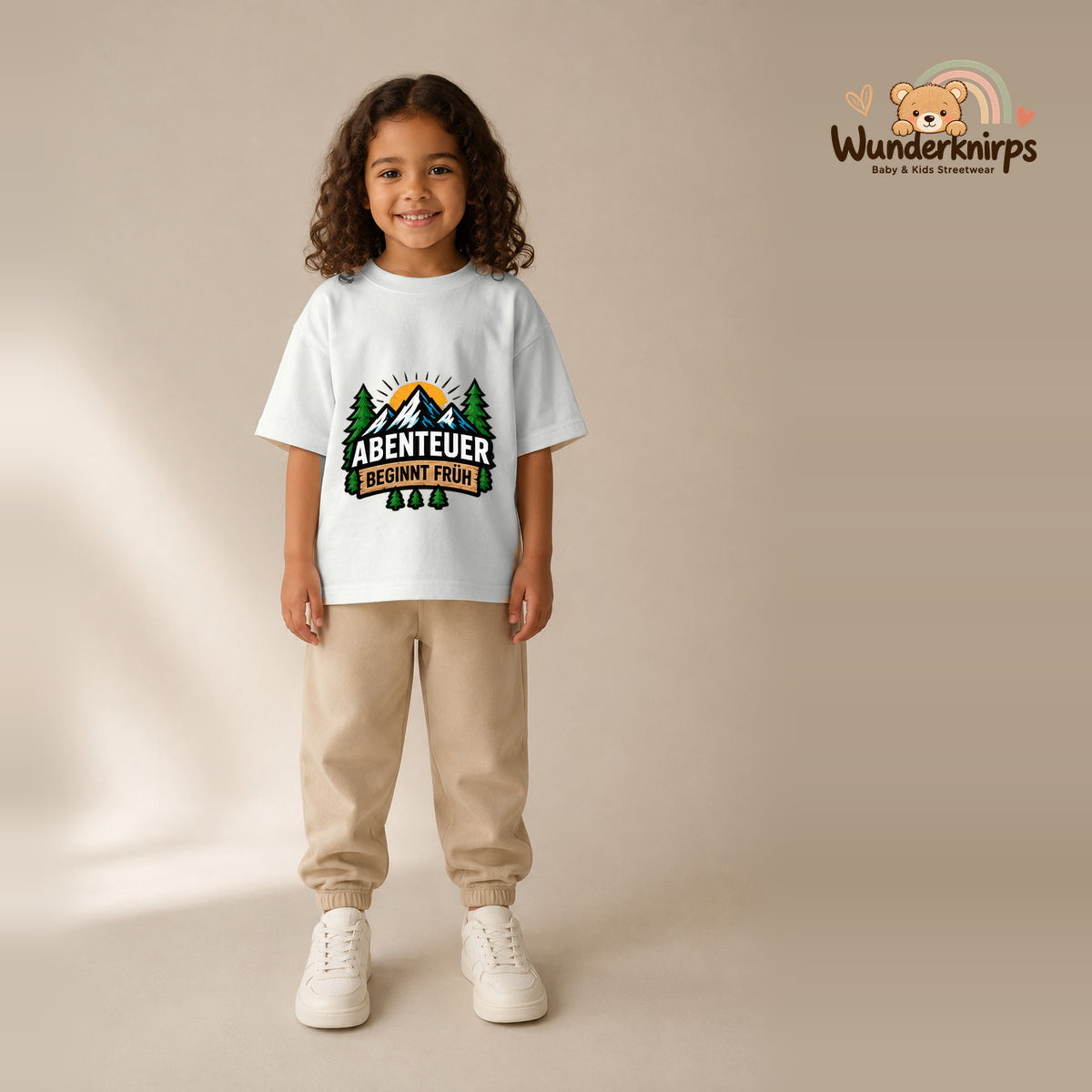 T-Shirt für Mädchen in Weiß mit Motiv „Abenteuer beginnt früh“, getragen von einem Kind – Wunderknirps.
