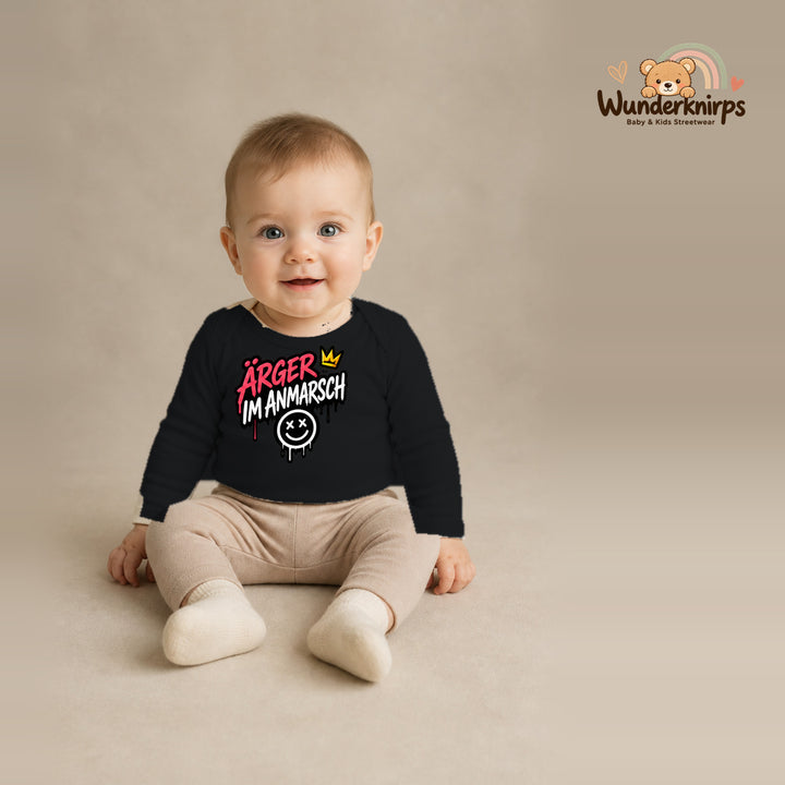 Babybody für Jungen in Schwarz mit Motiv „Ärger im Anmarsch“, getragen von einem Kind – Wunderknirps.