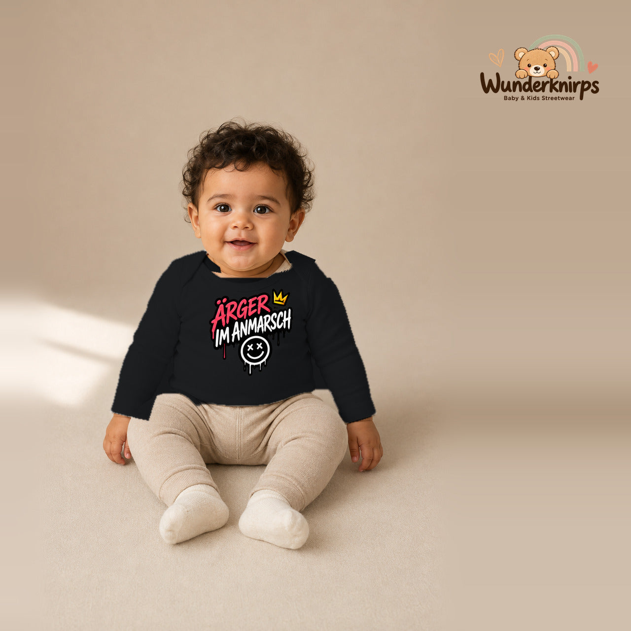 Babybody für Jungen in Schwarz mit Motiv „Ärger im Anmarsch“, getragen von einem Kind – Wunderknirps.